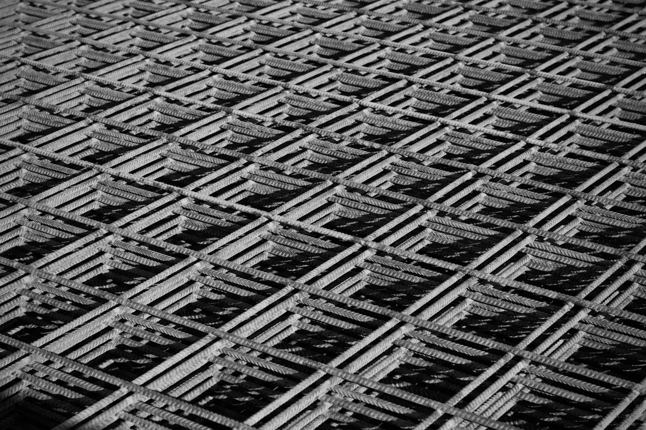 Black and white abstract close-up of interwoven metal grid pattern.